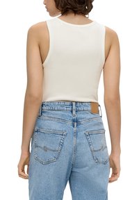 Weißes eng anliegendes Tanktop mit rundem Ausschnitt, kombiniert mit hoch taillierten hellblauen Jeans aus Denim mit Gesäßtaschen und dezenten Nähten.