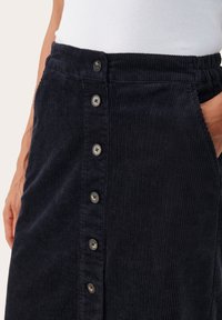 Tengerészkék kord szoknya egyenes szabással, gombos elülső záródással és oldalsó zsebekkel. Texturált anyag, függőleges bordázottsággal.