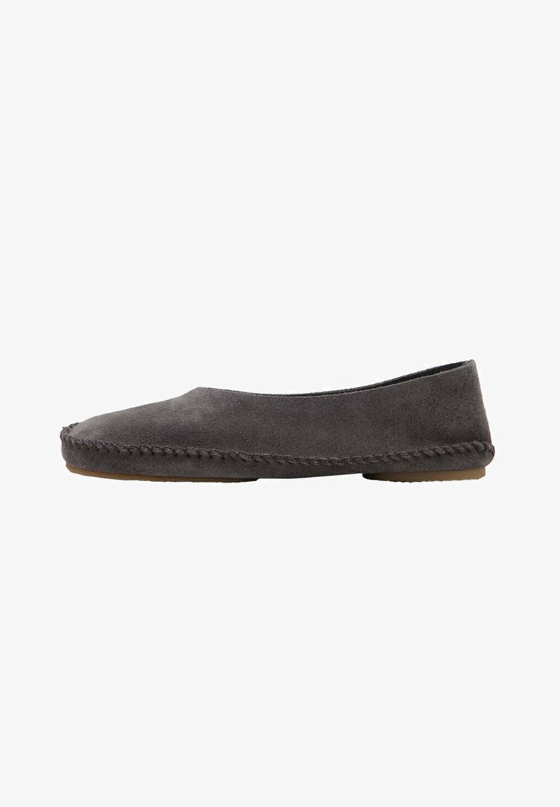 Chaussure plate style mocassin en daim gris foncé avec des détails cousus main visibles le long de la semelle et une semelle extérieure en caoutchouc à profil bas.