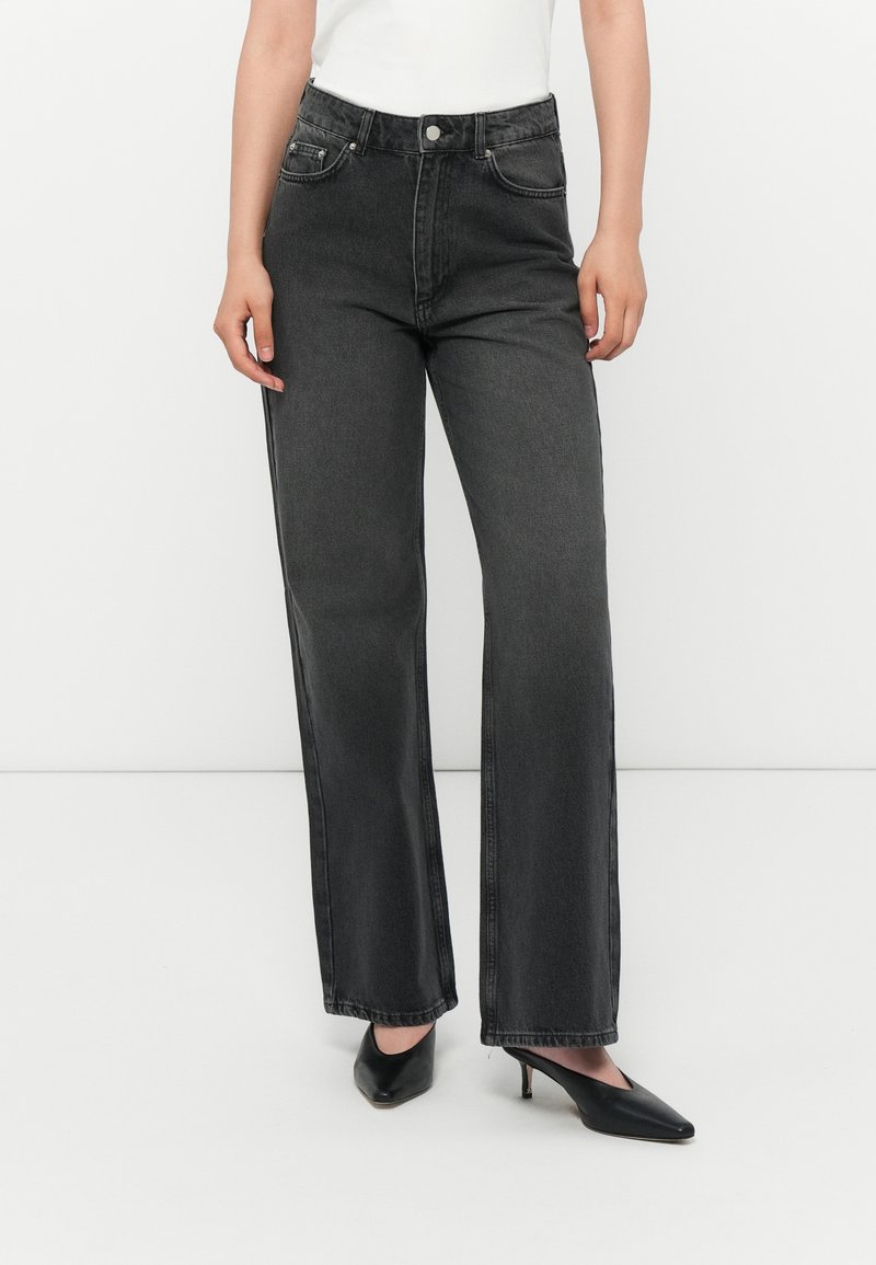 Høyt liv, vide denimjeans i mørkegrått med frontlommer og glidelås foran. Pare med svarte spisse hæler.