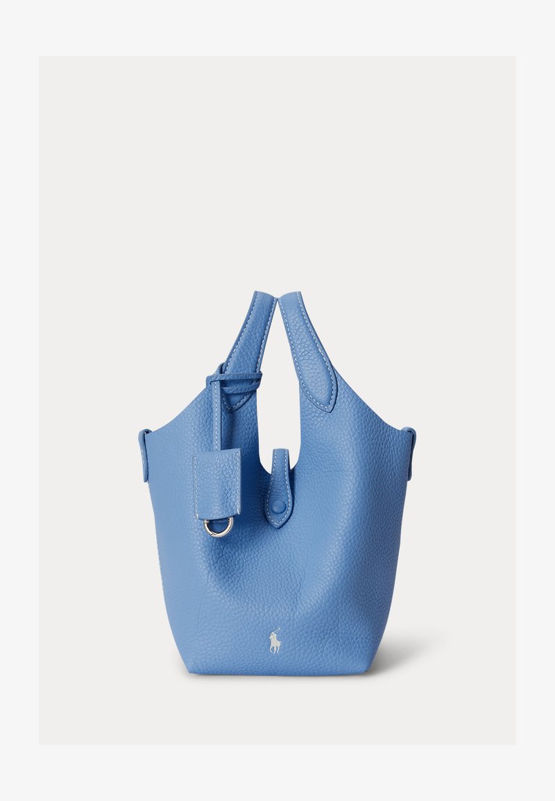 Μπλε υφασμάτινη δερμάτινη τσάντα τύπου κάδος με δύο λαβές, μπροστινή ετικέτα με μεταλλικό κρίκο και μικρό λευκό λογότυπο παίκτη πόλο στο κάτω κέντρο.