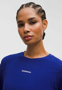Tricou din bumbac albastru cu guler rotund și logo-ul alb "lululemon" pe piept. Textură netedă și design cu un croi lejer.
