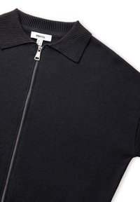 Černý svetr na zip s vroubkovaným límcem a manžetami, kovovým zipem a bílou značkovou etiketou uvnitř límce, která zní "IPEKYOL."