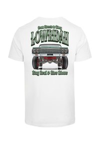 T-shirt blanche avec un graphique coloré d'une voiture lowrider et le texte "LOWRIDAH" et "Des rues à la gloire" au-dessus.