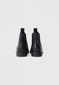 Černé kožené kotníkové boty s elastickými bočními panely, kulatou špičkou a texturovanou gumovou podrážkou. Na boku je viditelná voděodolná značka GORE-TEX.