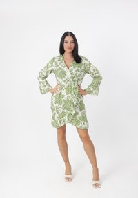 Vestido envolvente floral verde y blanco con mangas largas, con dobladillo rizado y cierre frontal con lazo, fabricado en tejido ligero.