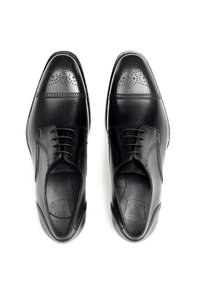 Chaussures de ville en cuir noir avec des perforations, design à lacets, bout rond et texture lisse. Présente des accents de couture sur les côtés.