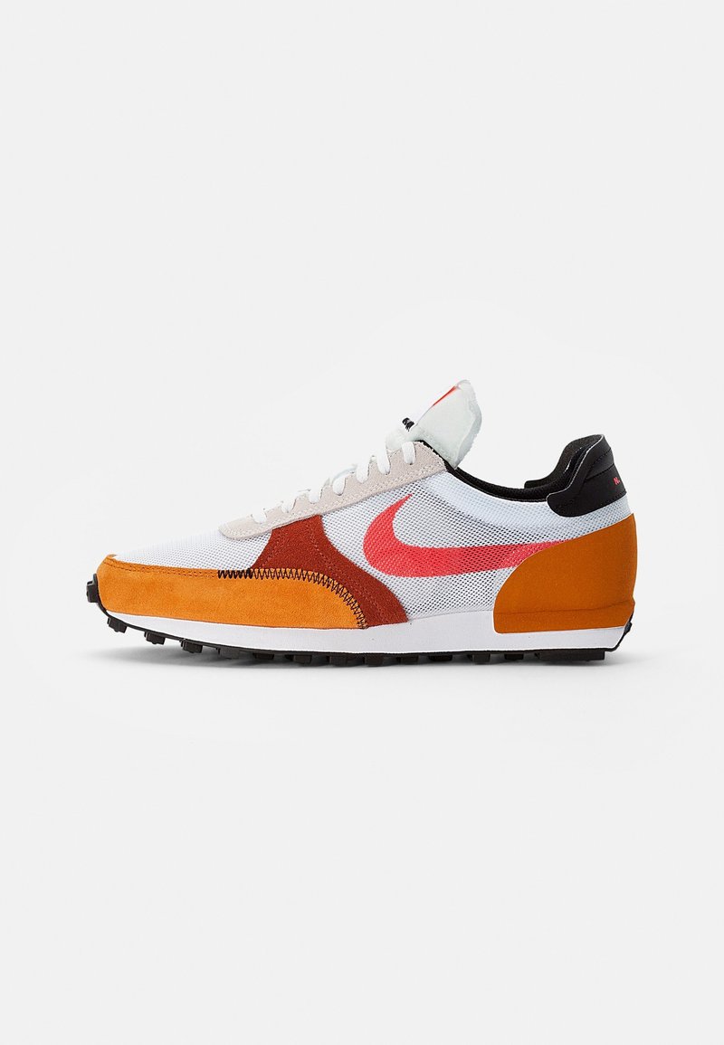 Nike sneaker with a white mesh upper, orange suede accents, red branding, and a black heel. Features a rubber sole with traction.