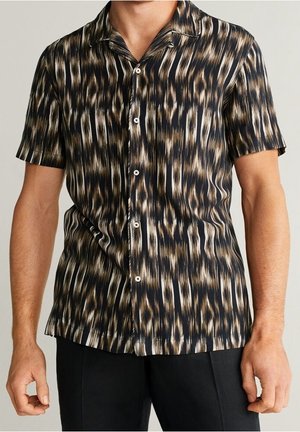 Męska koszula z krótkim rękawem na guziki z abstrakcyjnym wzorem w paski w kolorze czarnym, brązowym i beżowym, noszona z czarnymi spodniami.