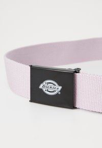 Rosa gewebter Stoffgürtel mit einer schwarzen, rechteckigen Metallschnalle, die das "Dickies"-Logo in Weiß zeigt. Glatte Textur mit robuster Verarbeitung.