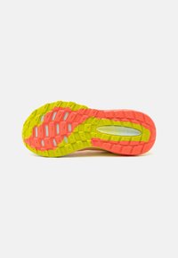 Semelle de chaussure en jaune vif et rose, présentant une surface texturée avec un motif en zigzag, conçue pour l'adhérence et la traction.