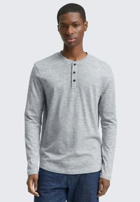 Szara koszula henley z długim rękawem, z trzema czarnymi guzikami przy kołnierzy, charakteryzująca się teksturowanym materiałem i zaokrąglonym hemem.