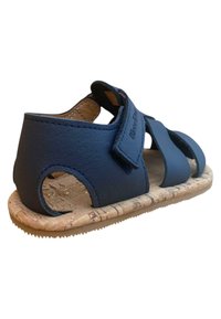 Sandalias azul marino de cuero con suela de corcho, que presentan cortes y correas ajustables para un ajuste seguro. La vista lateral muestra los detalles del diseño.
