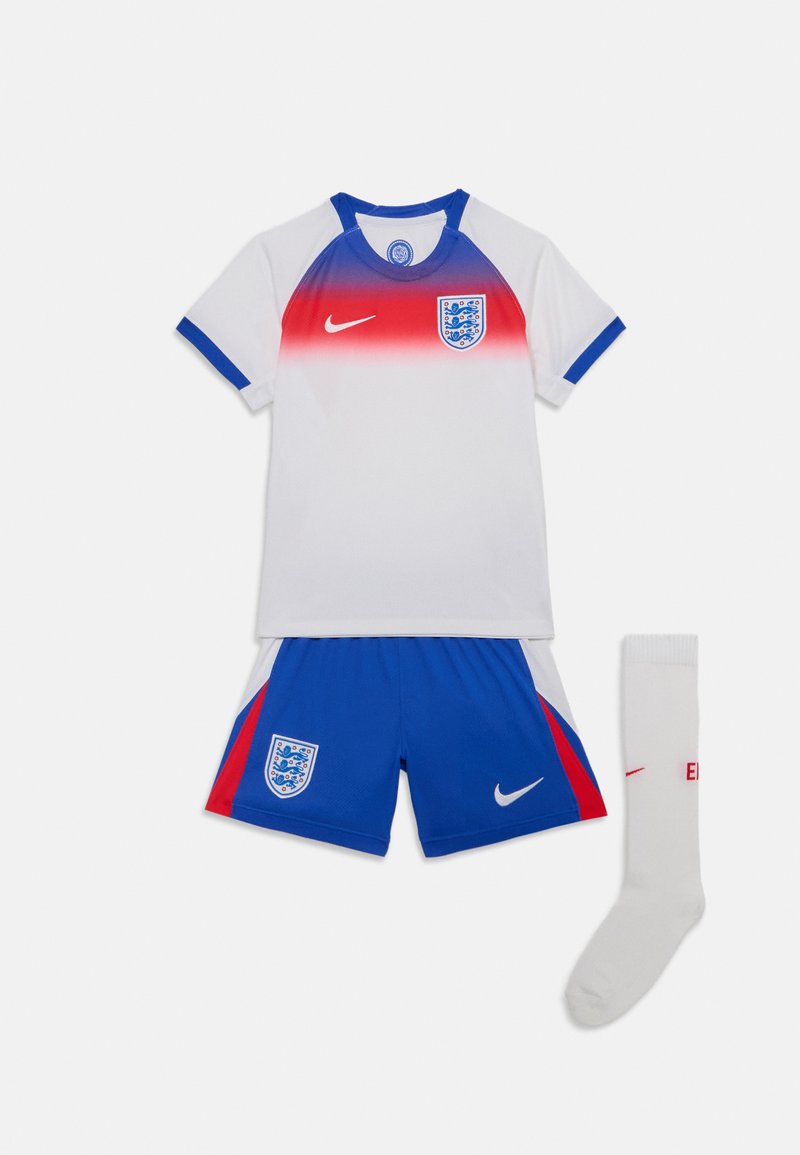 Ungdomsfotbollskit bestående av en vit tröja med röd gradient och blå detaljer, i kombination med blå shorts och en vit strumpa med röd logotyp.