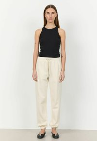 Svart ribbad linne tillsammans med off-white joggers med elastisk midja. Joggers har justerbart snöre och muddar. Svarta slip-on skor.