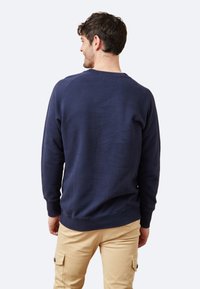 Sudadera de color azul marino hecha de mezcla de algodón, con mangas largas, puños acanalados y un cuello redondo, con una textura suave y un corte clásico.