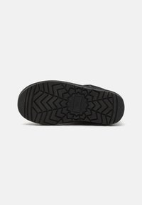 Suela de zapatilla negra con patrones de tracción profundos, que presenta un diseño en zigzag para mejorar el agarre. El material es caucho, lo que proporciona durabilidad y adherencia.