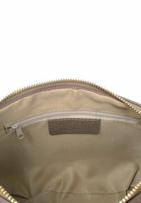 Pochette in tessuto beige con zip e rifiniture dorate. L'interno presenta una morbida fodera beige, una piccola tasca con zip e un'etichetta marrone testurizzata.