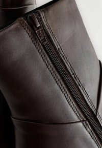 Stivaletto in pelle marrone con cerniera laterale; presenta dettagli di cucitura e un design elegante. Texture liscia, forma arrotondata, ideale per un look casual.