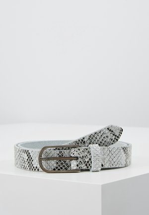 Ceinture grise à motif peau de serpent enroulée avec une boucle en métal argenté posée sur une surface blanche.