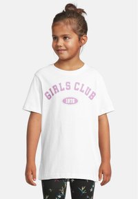 Hvit bomulls t-skjorte med "GIRLS CLUB" og "1976" i lys rosa tekst, korte ermer, rund hals, sammen med mønstrede svarte leggings.