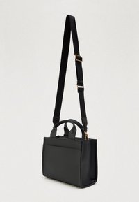 Μαύρη ορθογώνια τσάντα ώμου με δύο κοντές λαβές και ρυθμιζόμενο μακρύ λουρί, κρεμασμένη σε απλό φόντο.