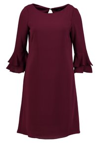 Robe bordeaux en tissu doux, avec un col rond, un détail dos en forme de goutte, et des manches évasées et superposées. Longueur midi.
