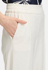 Witte, lichtgewicht broek met een elastische tailleband en zijzak, met een gladde textuur en strakke lijnen.