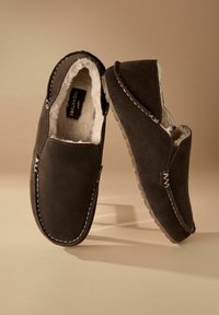 Brune ruskindslippers med en blød indvendig foring, syede detaljer og et slip-on design. Tekstureret sål for godt greb og komfort.