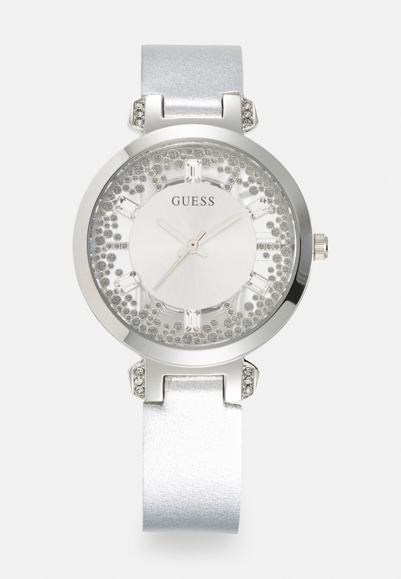 Silverfärgad damklocka med rund metallkapsel, glittrande bezel och en glittrig vit urtavla. Utrustad med en slät silverrem och kristallaccenter.