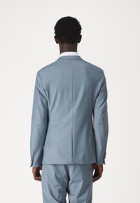 Lichtblauw kostuum met een slim fit ontwerp. De blazer heeft een enkele split aan de achterkant, een contrasterende witte kraag en een knoopsluiting bij de mouwen.