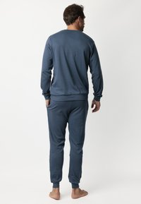 Conjunto de jogger en azul marino hecho de tela suave, con cuello redondo, mangas largas, puños y cinturilla elásticos. Sin patrones ni acentos visibles.
