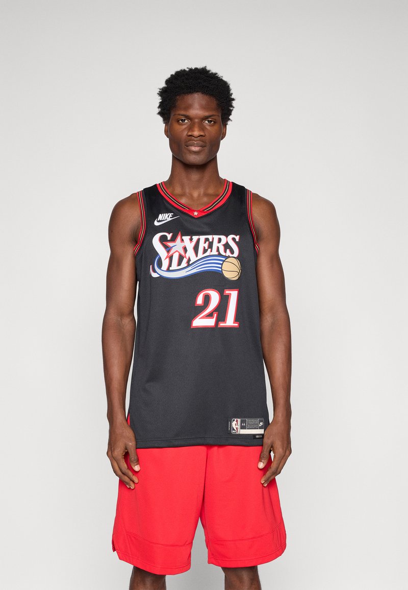 Black basketball jersey featuring "Sixers" in red and blue lettering, number 21, paired with red shorts. Material appears breathable mesh.