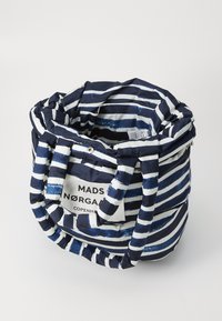 Rund stoffveske med marineblå og hvite striper, som har solide håndtak og en etikett med "MADS NØRGAAARD COPENHAGEN" trykket på.