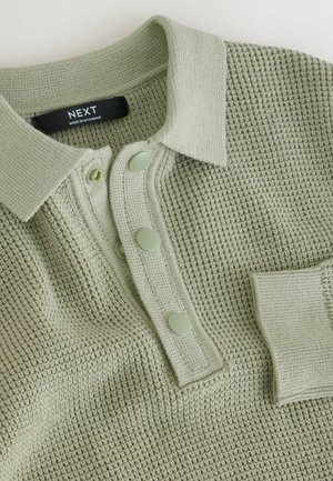 Light green textured polo shirt with a collared neck, three matching buttons, and a pocket on the left side. Fabric has a waffle pattern.