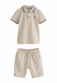 Polo beige avec patte de boutonnage et finition verte, associé à un short beige assorti avec taille élastique et poches latérales.