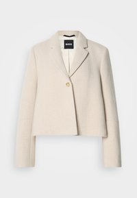 Περικομμένο μπεζ σακάκι με υφή, γιακάδες με εγκοπή, κλείσιμο με ένα κουμπί και μαύρη ετικέτα επωνυμίας στο εσωτερικό.