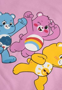 Kolorowe kreskówkowe misie na różowym tle; niebieski miś z wzorem chmur, różowy miś z tęczą, żółty miś z motywem słońca.