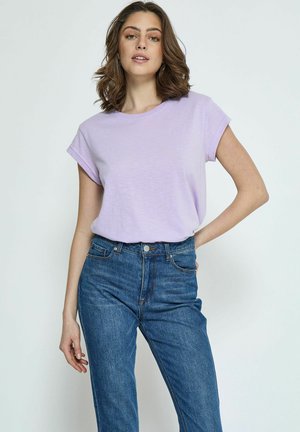 Lavendel t-shirt met korte mouwen van lichtgewicht stof, gecombineerd met hoge blauwe spijkerbroek met een knoop aan de voorkant en zakdetails.
