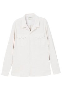 Chemise à manches longues beige clair en tissu texturé. Elle présente un col avec revers et deux poches avant à rabat.