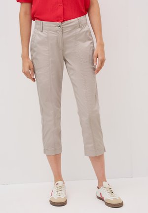 Pantalons beiges coupés avec un devant plat, des poches et des détails cousus. Fabriqués en tissu léger, dotés d'une fermeture à bouton et à zip.