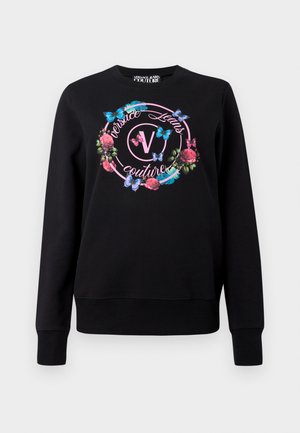 Črna dukserica z grafičnim dizajnom cvetja in metuljev, z logotipom na sredini. Rebrasti manšeti in rob zagotavljajo strukturo.