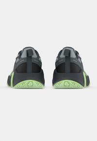 Ζεύγος γκρίζων και μαύρων αθλητικών παπουτσιών με φωσφορίζουσες πράσινες σόλες, που προβάλλονται από το πίσω μέρος, επιδεικνύοντας τα λουράκια γύρω από τη φτέρνα και την υφή του πέλματος.