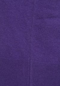 Fialová pletená látka s jemnými variacemi textury, obsahující žebrovaný okraj a hladké části; nejsou vidět žádné výrazné vzory ani kovové části.