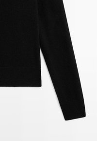 Maglione nero realizzato in un materiale morbido, caratterizzato da un design semplice con scollatura rotonda e maniche lunghe. Tessuto liscio, dettagli di cucitura minimi.