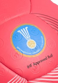 Röd handboll med texturerad yta, med en blå emblem och guldaccent. Texten säger "IHF-godkänd boll" nära botten.