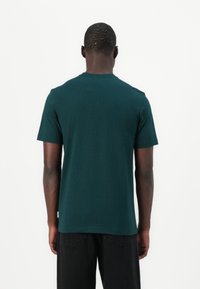 Green cotton t-shirt with short sleeves and a crew neckline. Smooth texture, standard fit, viewed from the back. No visible patterns or accents.