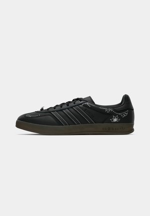 Black athletic shoes with leather upper, featuring three white stripes, floral embroidery on the side, and a rubber sole.