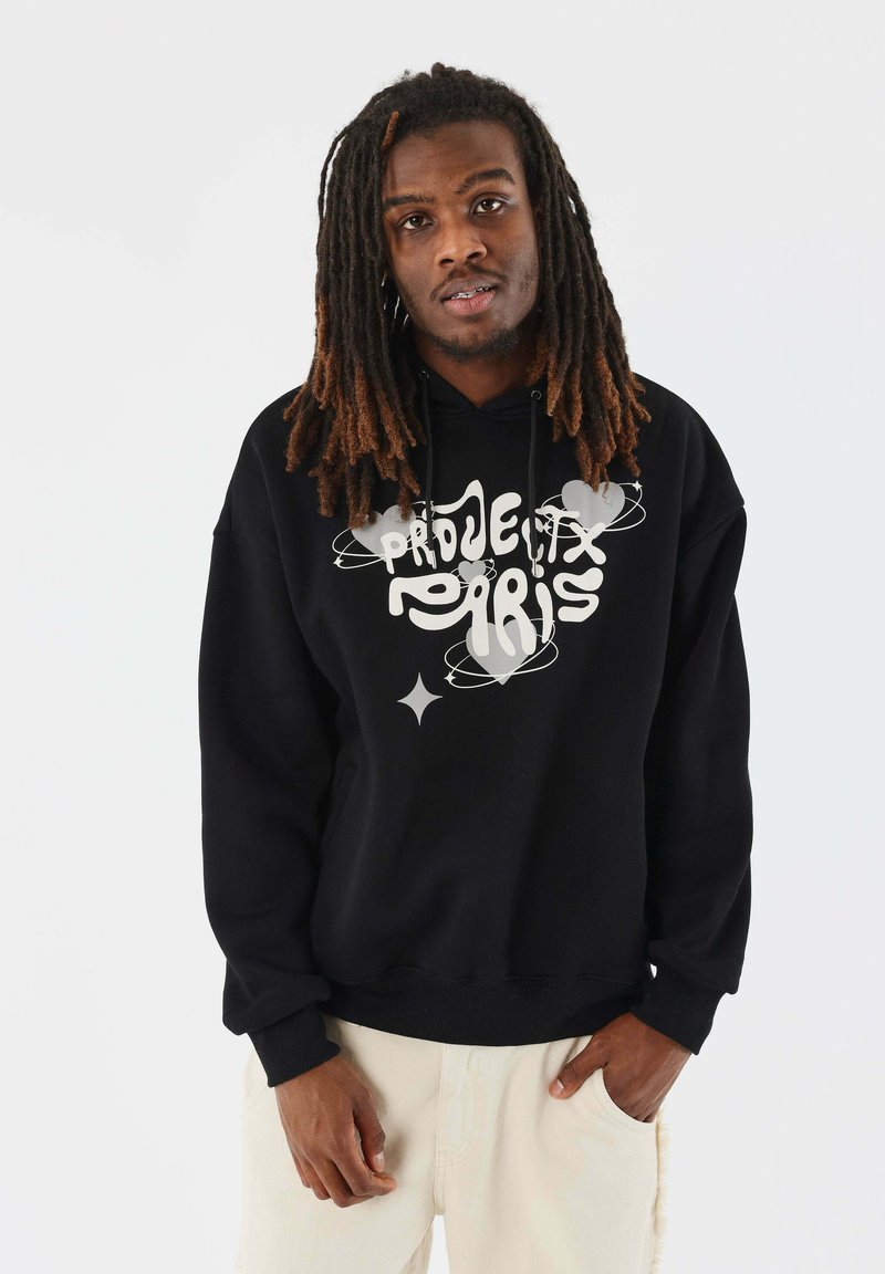 Sudadera negra con un texto gráfico que dice "Pride" y "Paris", con un corte casual, capucha con cordón y puños acanalados. Fondo blanco.