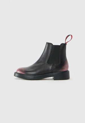 Stivale alla caviglia in pelle nera con pannello laterale elasticizzato, punta e tacco tinti di rosso, suola nera e linguetta rossa sul retro.